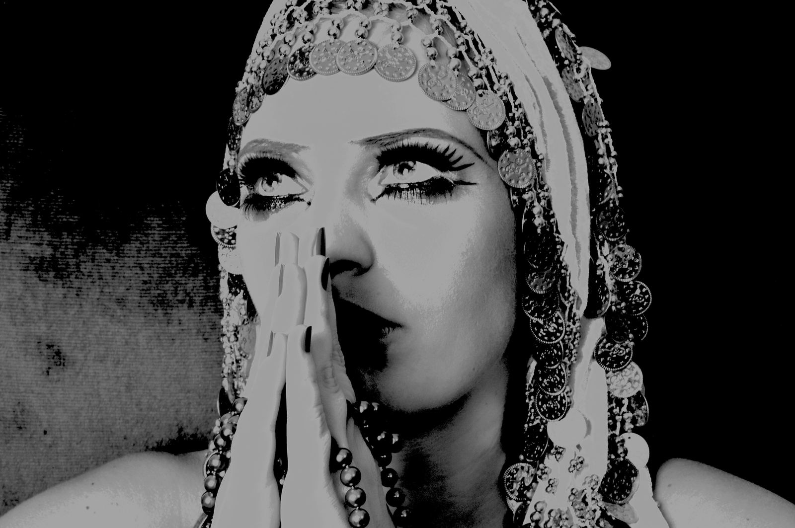 Black and white portrait with coin headdress and praying hands